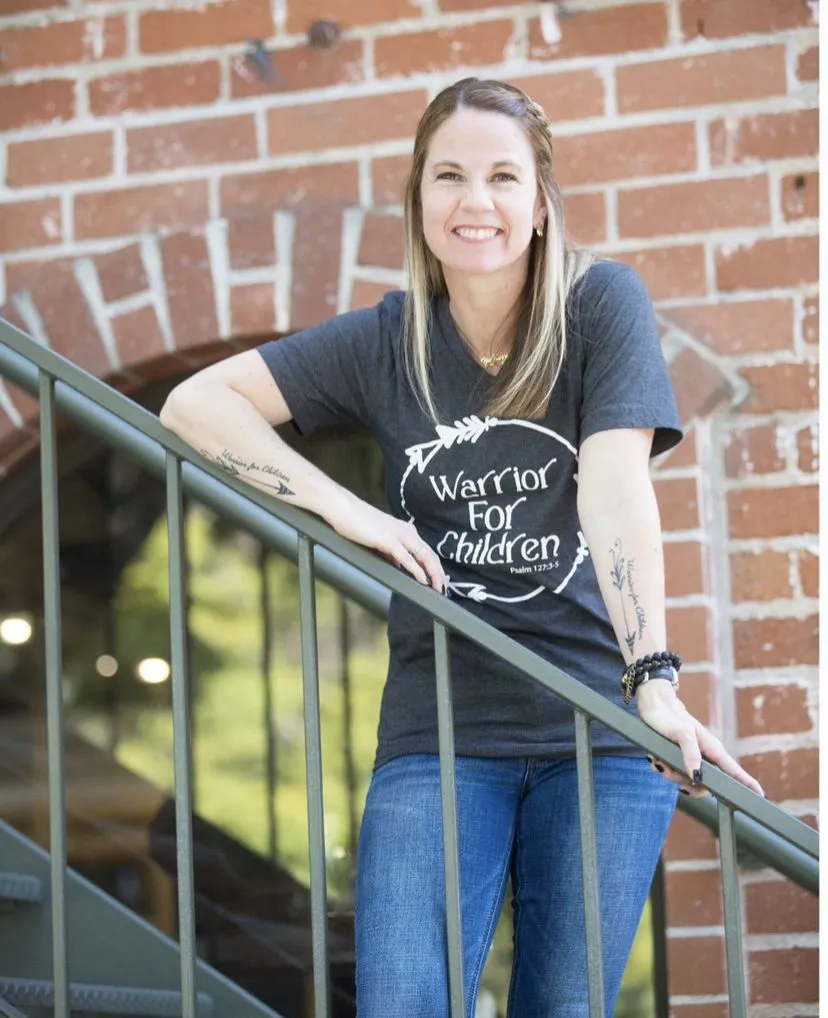 Jenn Corbett standing on a stairway in front of a brick wall