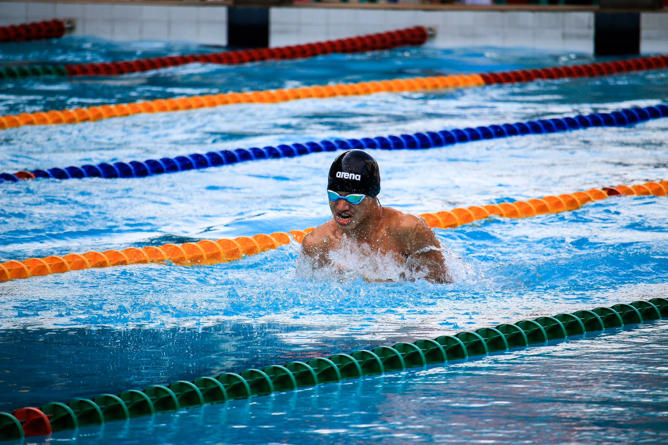 Male swimmer racing breaststroke in a pool.