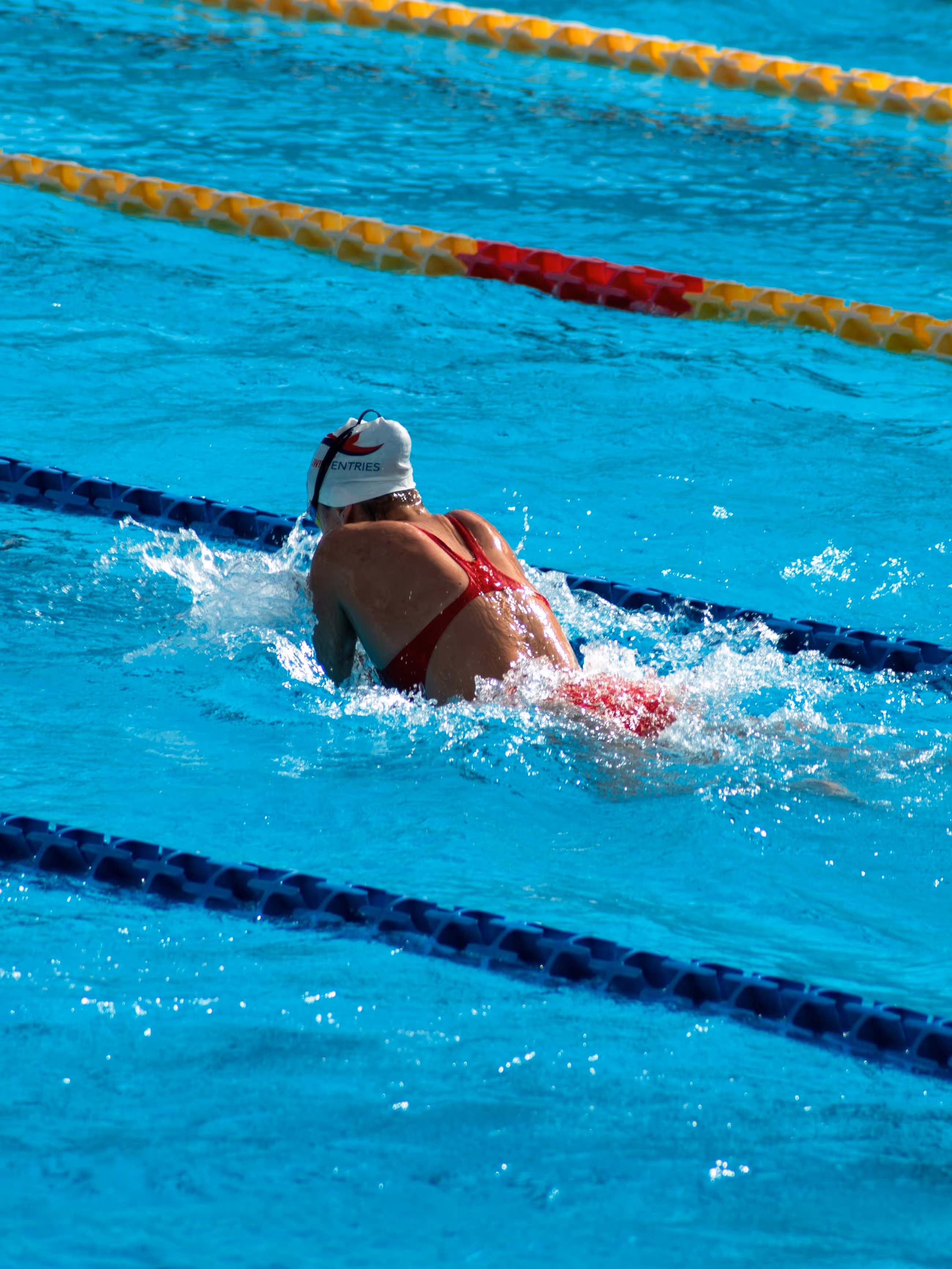 Female swimmer racing breaststroke in a pool.
