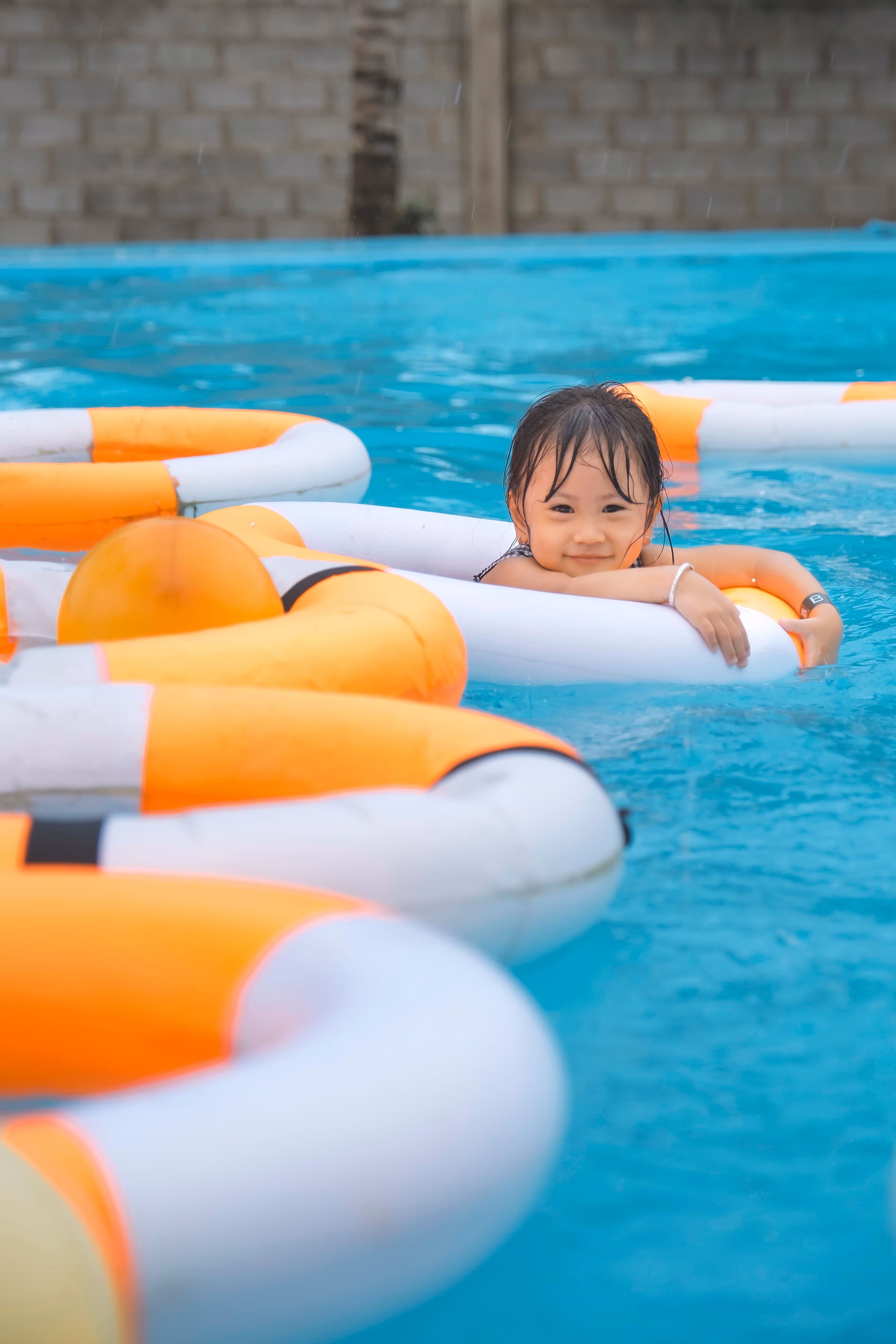 Child holding onto a float in a pool.