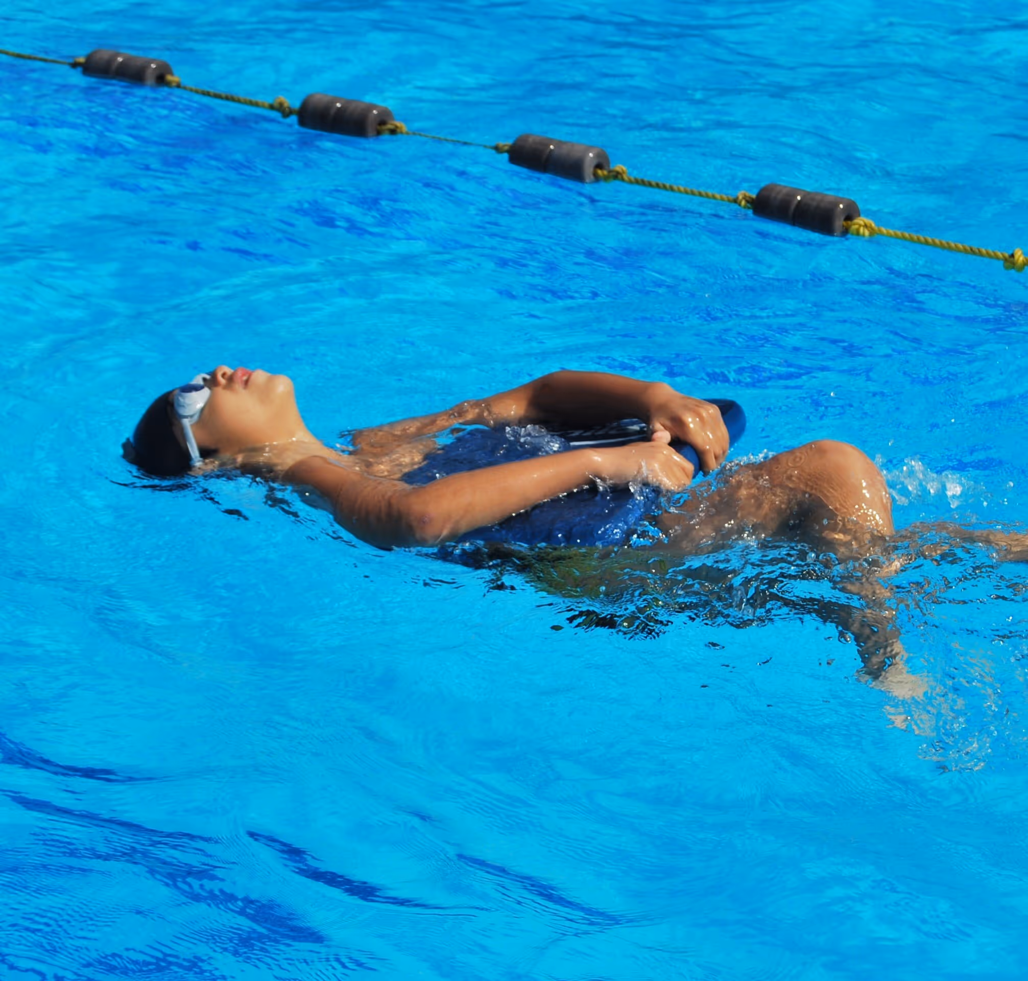 Child swimming on their back with a kickboard.