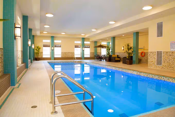 Indoor swimming pool with tiled walls and seating area.