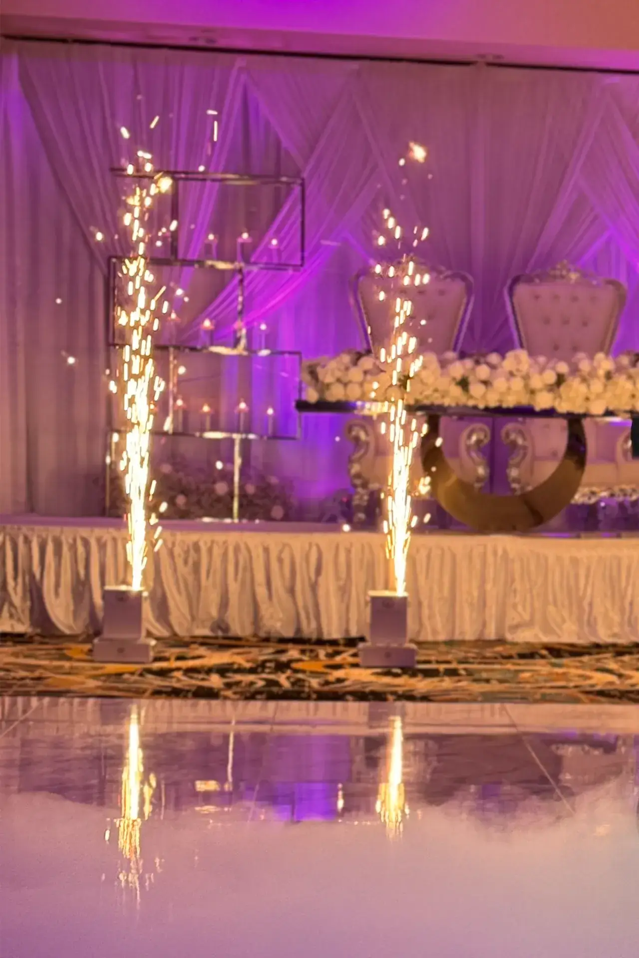 A photo of a head table with sparklers shooting in front