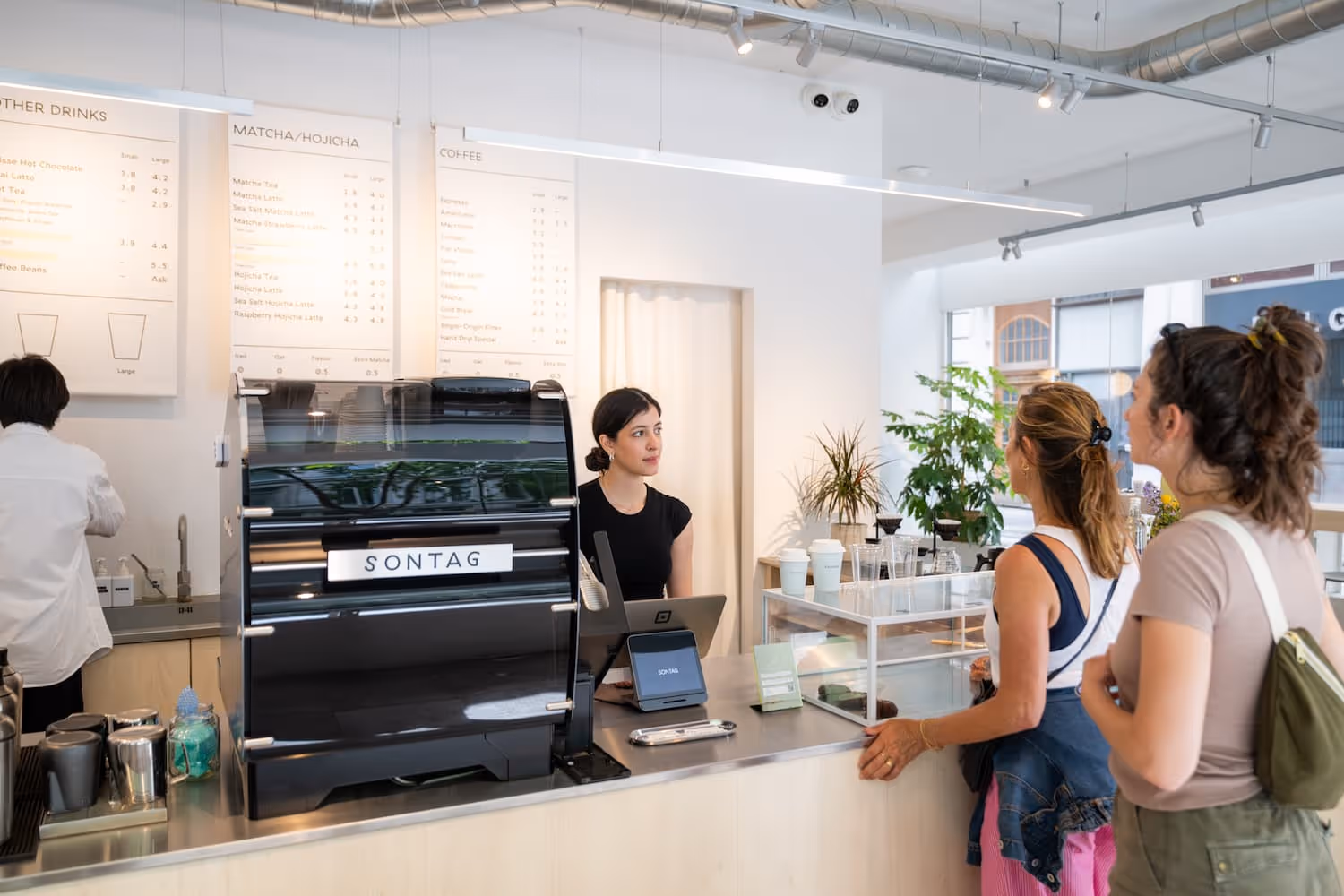 Shotmaster machine in foreground, barista pouring milk behind. 