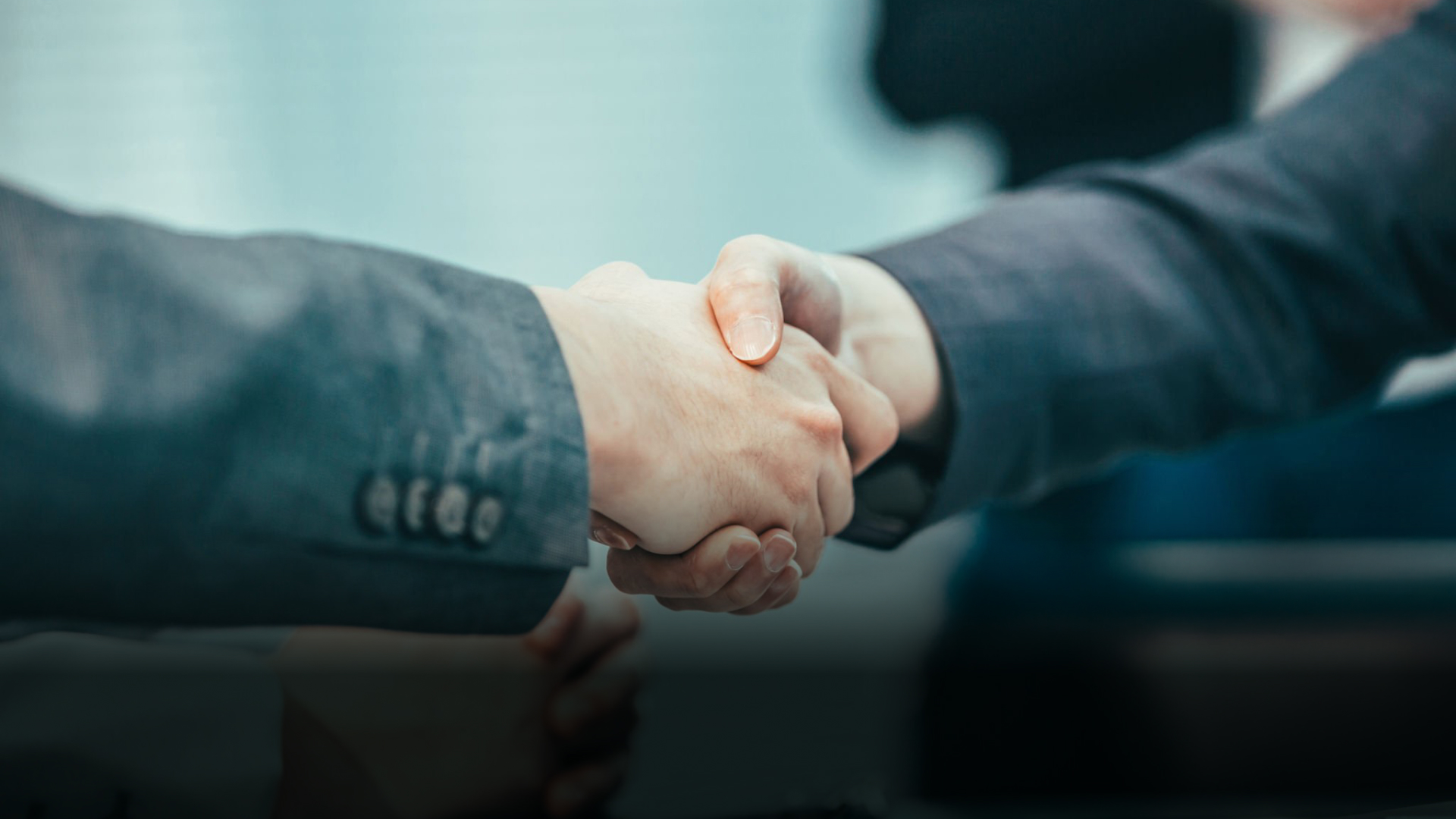 Two people shaking hands across a desk, representing the working relationship between a dental lab and a doctor.