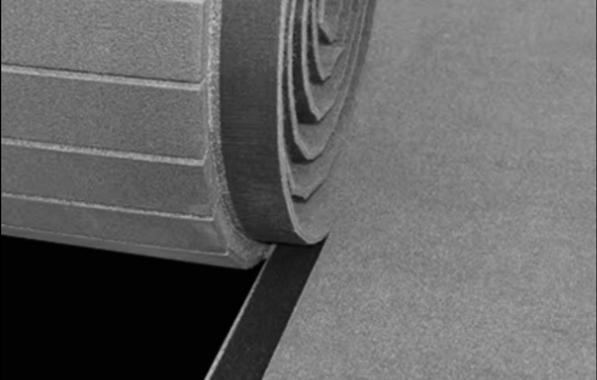 Close-up of a rolled-up gray textured mat or fabric partially unrolled on a flat surface.