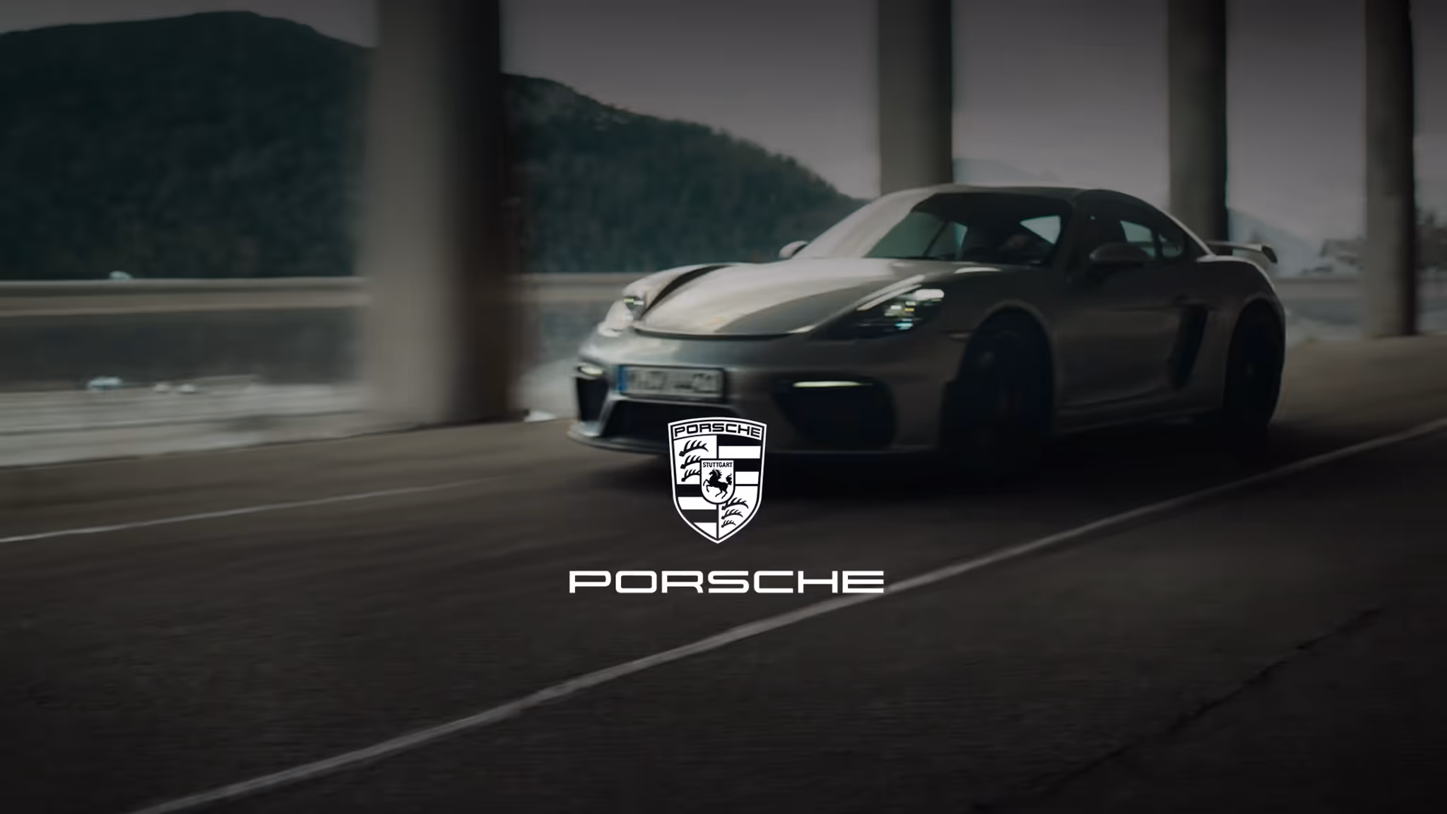 Silver Porsche sports car driving in a dimly lit tunnel with the Porsche logo and text overlay.