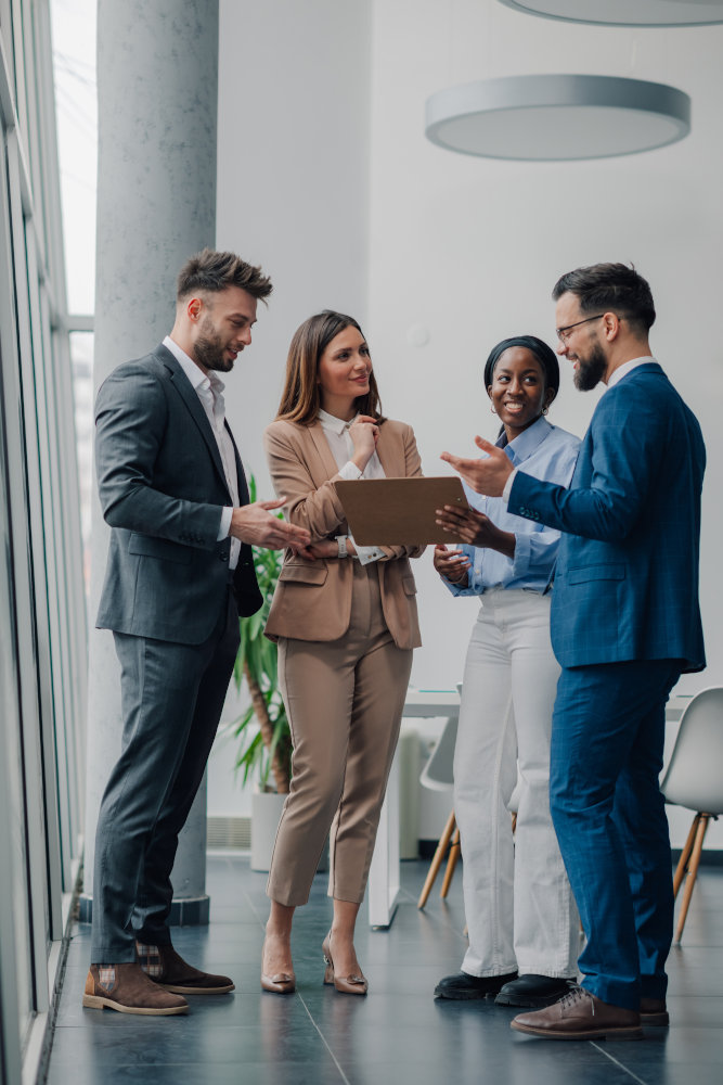 Four business professionals having a discussion in a modern office with natural lighting