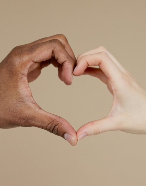 Two hands forming a heart shape against a neutral background