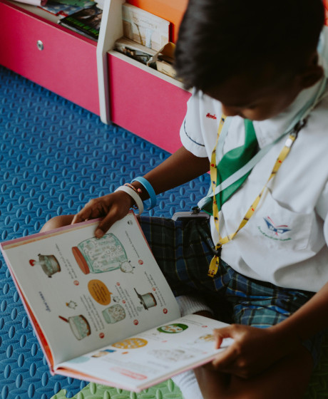 Child in a school uniform reading an illustrated book
