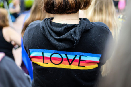 Person wearing a black hoodie with a rainbow “LOVE” design on the back