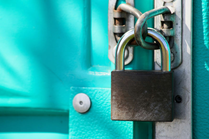 Close-up of a metal padlock securing a turquoise door, representing secure access to sensitive information.