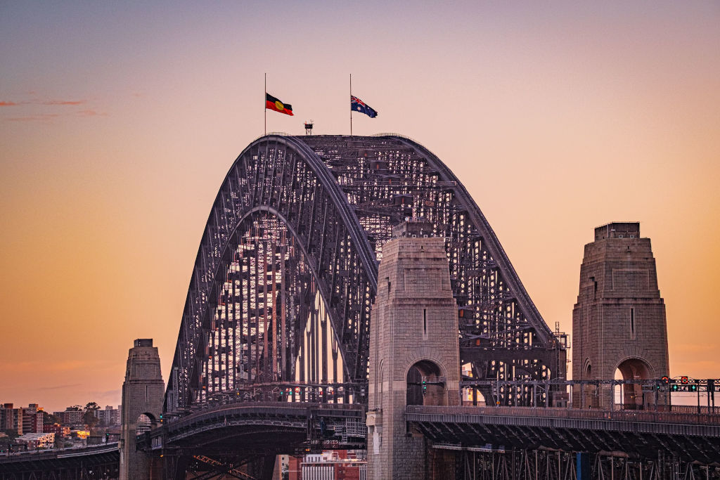 Iconic view of Sydney Harbour Bridge with flags at sunset