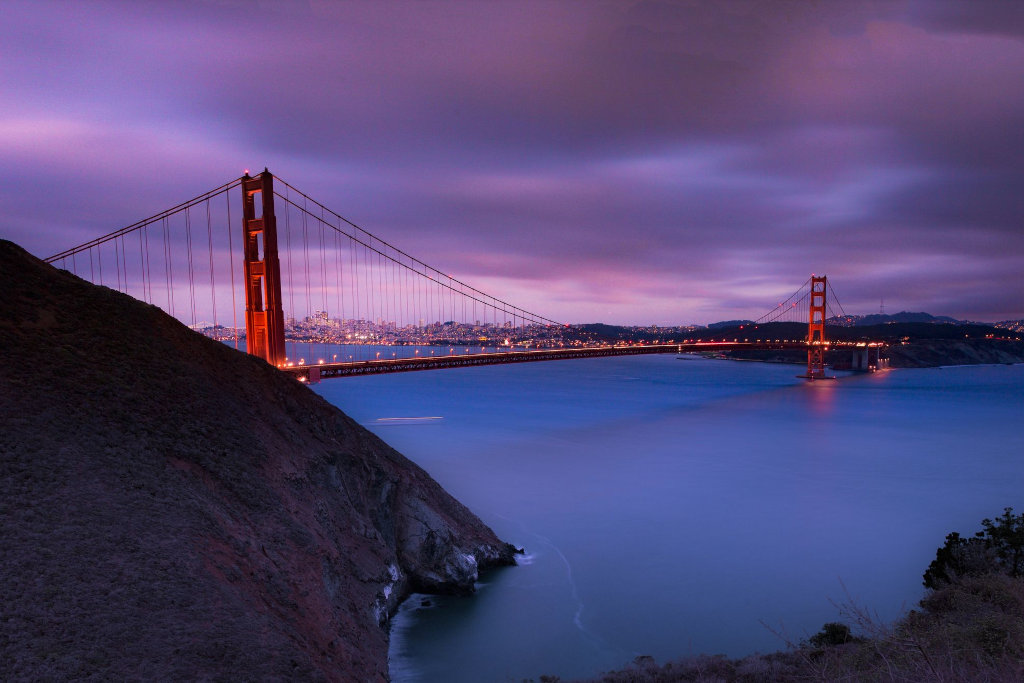 View of the Golden Gate Bridge at dusk with coastal landscape