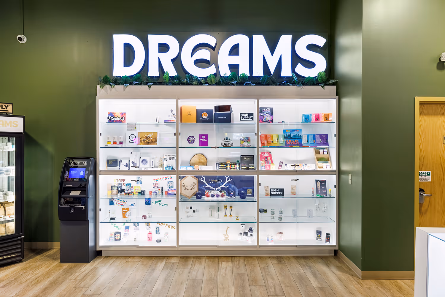 Illuminated "DREAMS" sign above a display case of cannabis products