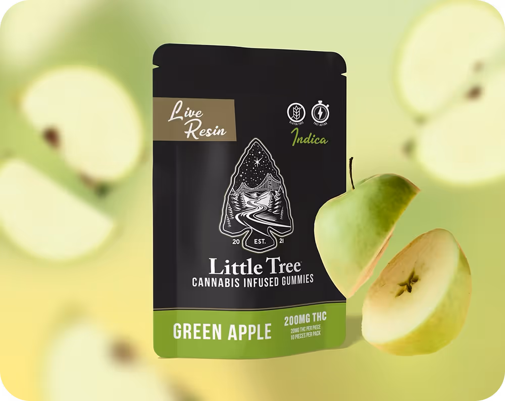 Green apple Little Tree gummies, black package with a sliced apple in front of it floating on a green apple pattern background