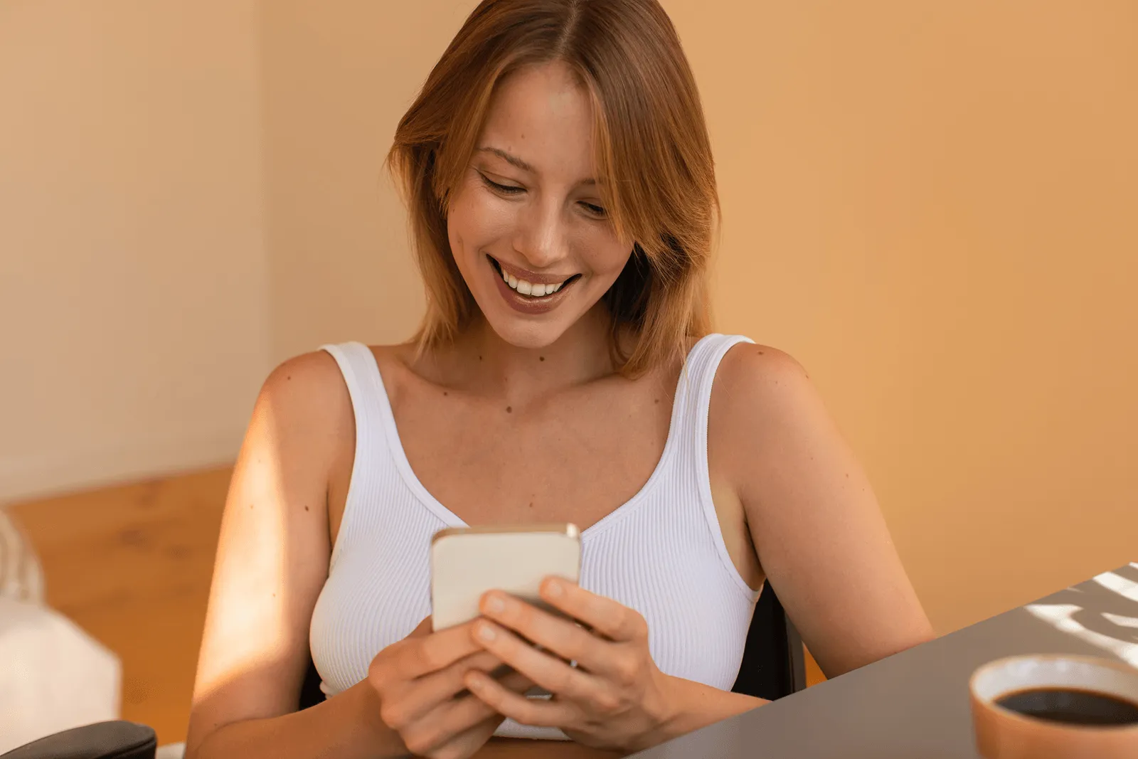 A woman sitting at a table looking at her cell phone.