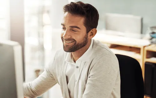 A man sitting in front of a computer smiling.
