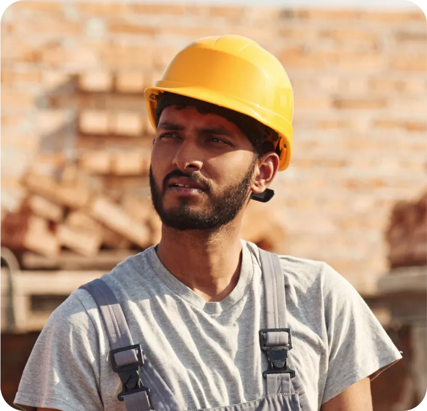 A man wearing a hard hat and overalls.