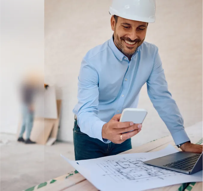 A man in a hard hat looking at a laptop.
