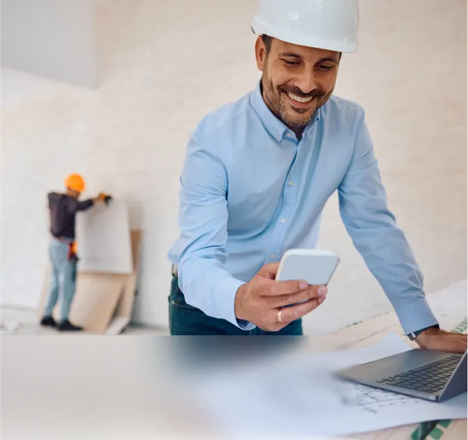A man in a hard hat looking at a laptop.