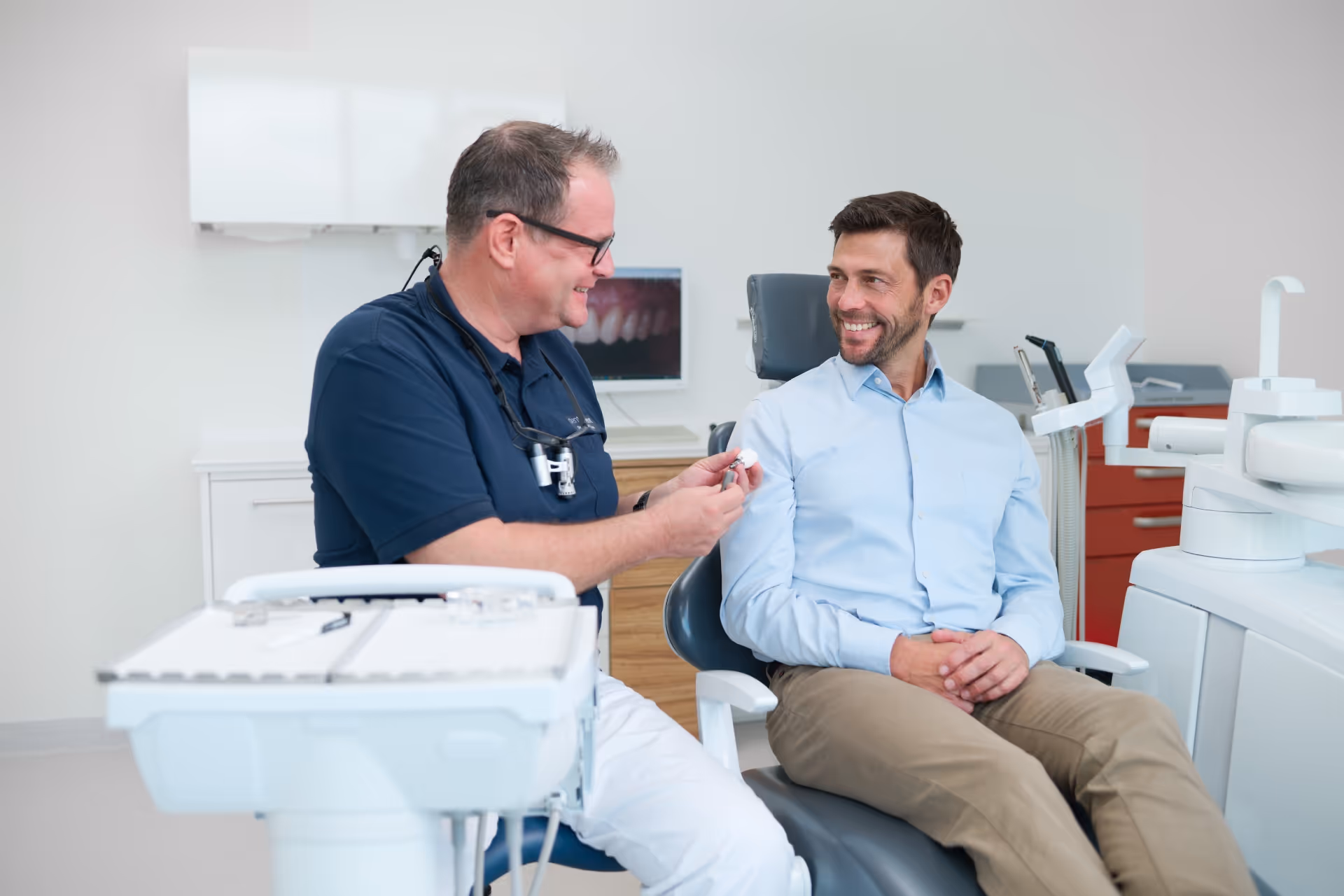 Zahnarzt erklärt Implantatbehandlung an einem Modell