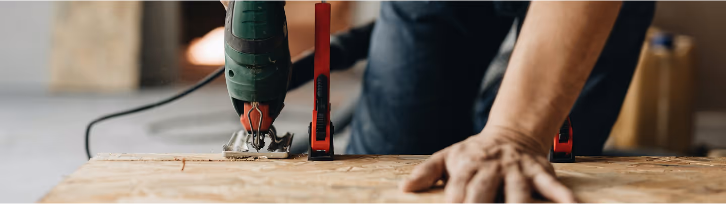 Photographie d'un homme qui découpe du parquet.
