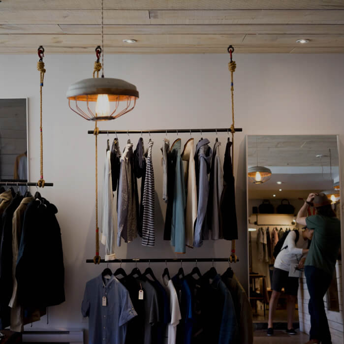 A person taking a picture of a clothing rack.