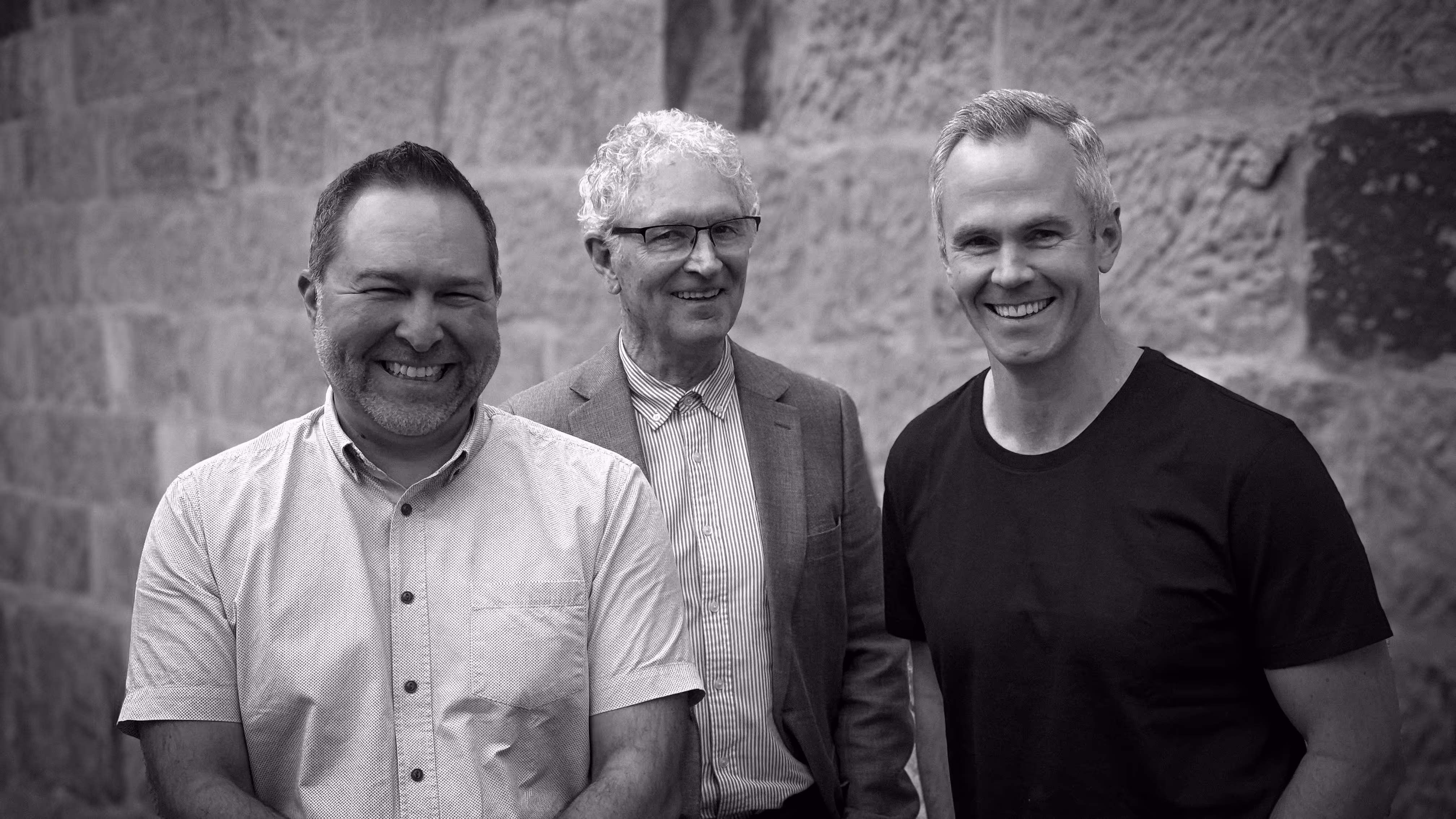 Three men standing together outdoors. From left to right: Adam Nordinson, Gil Sawford, and Matt Fishburn. Black and white photograph.