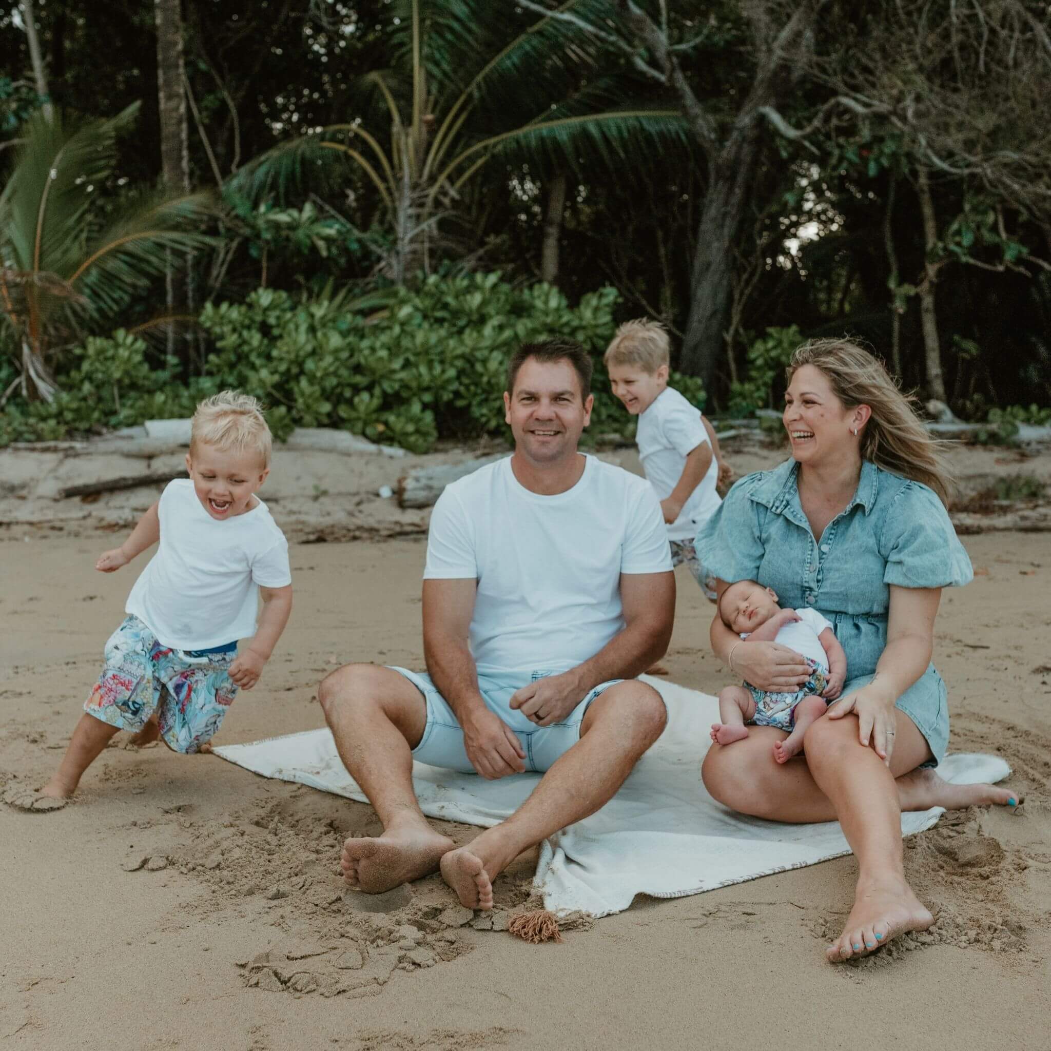 A family sitting on a blanket on the beach.