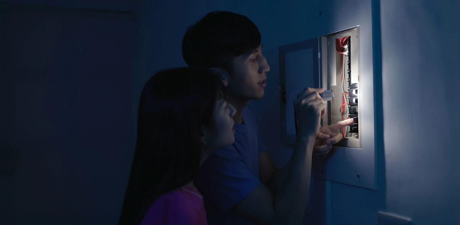 Photo of two people looking through a breaker during a power outage