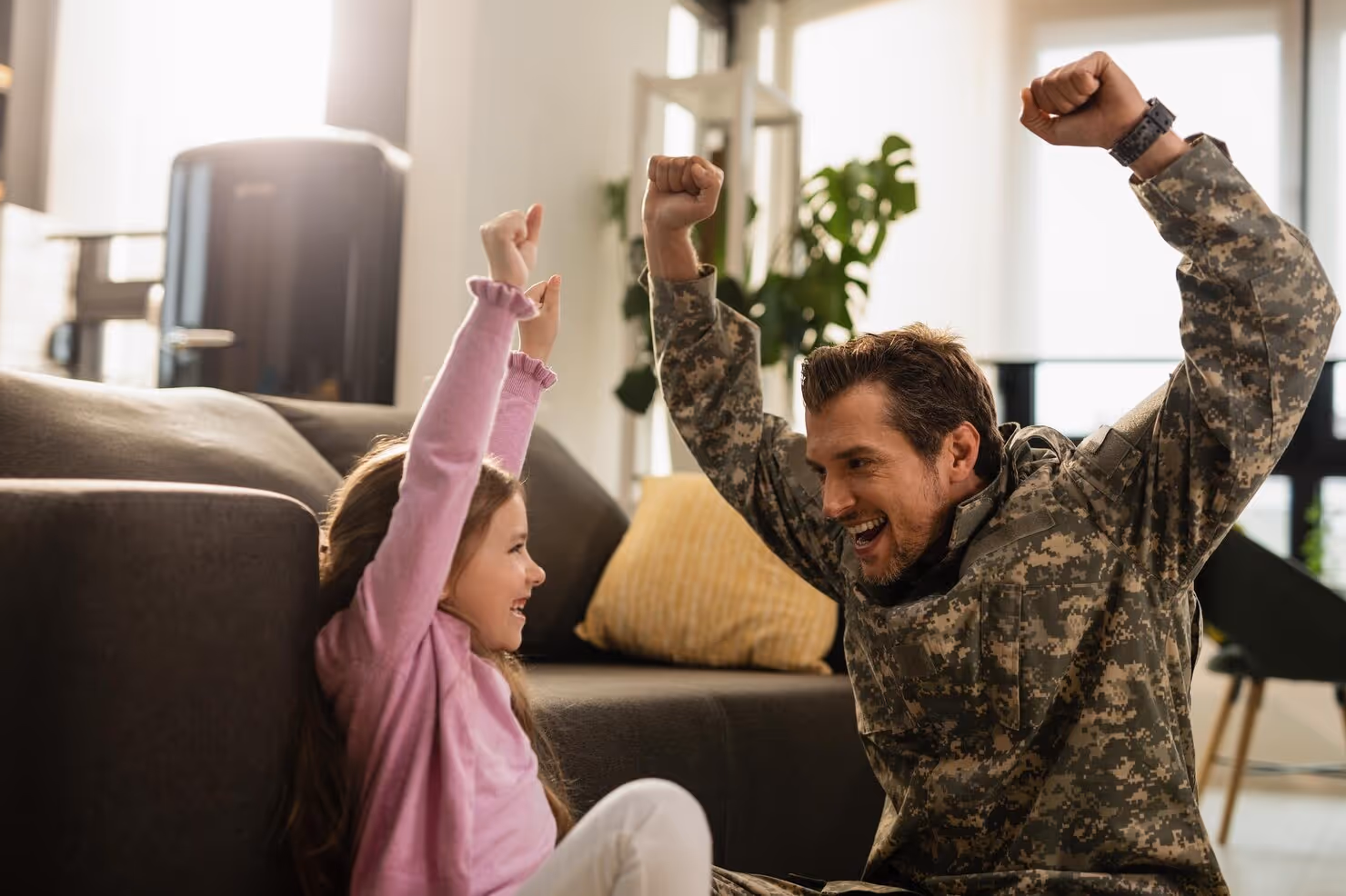 Man in military uniform and young girl celebrating together indoors.