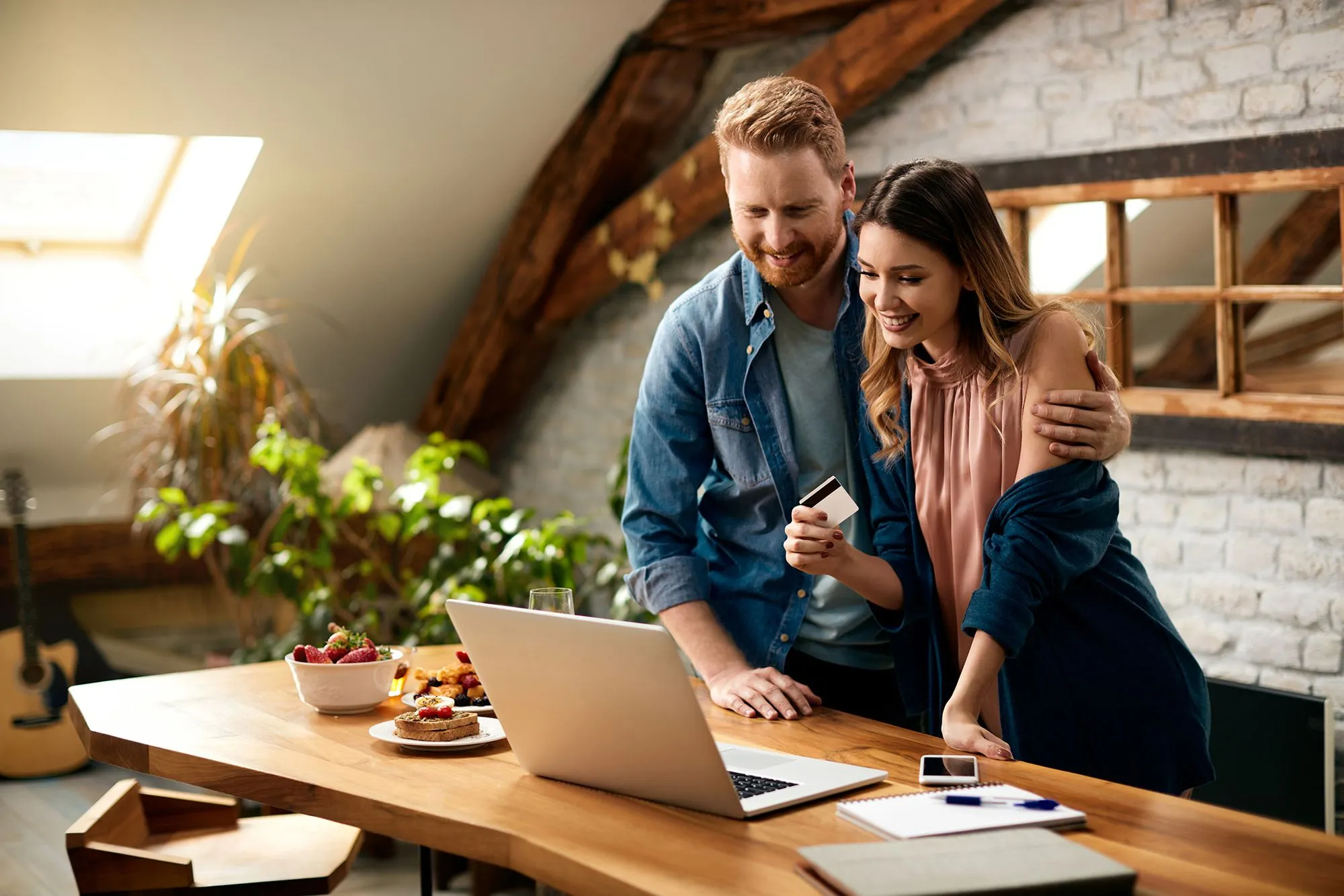 Smiling couple looking at a laptop together, planning home renovation financing.
