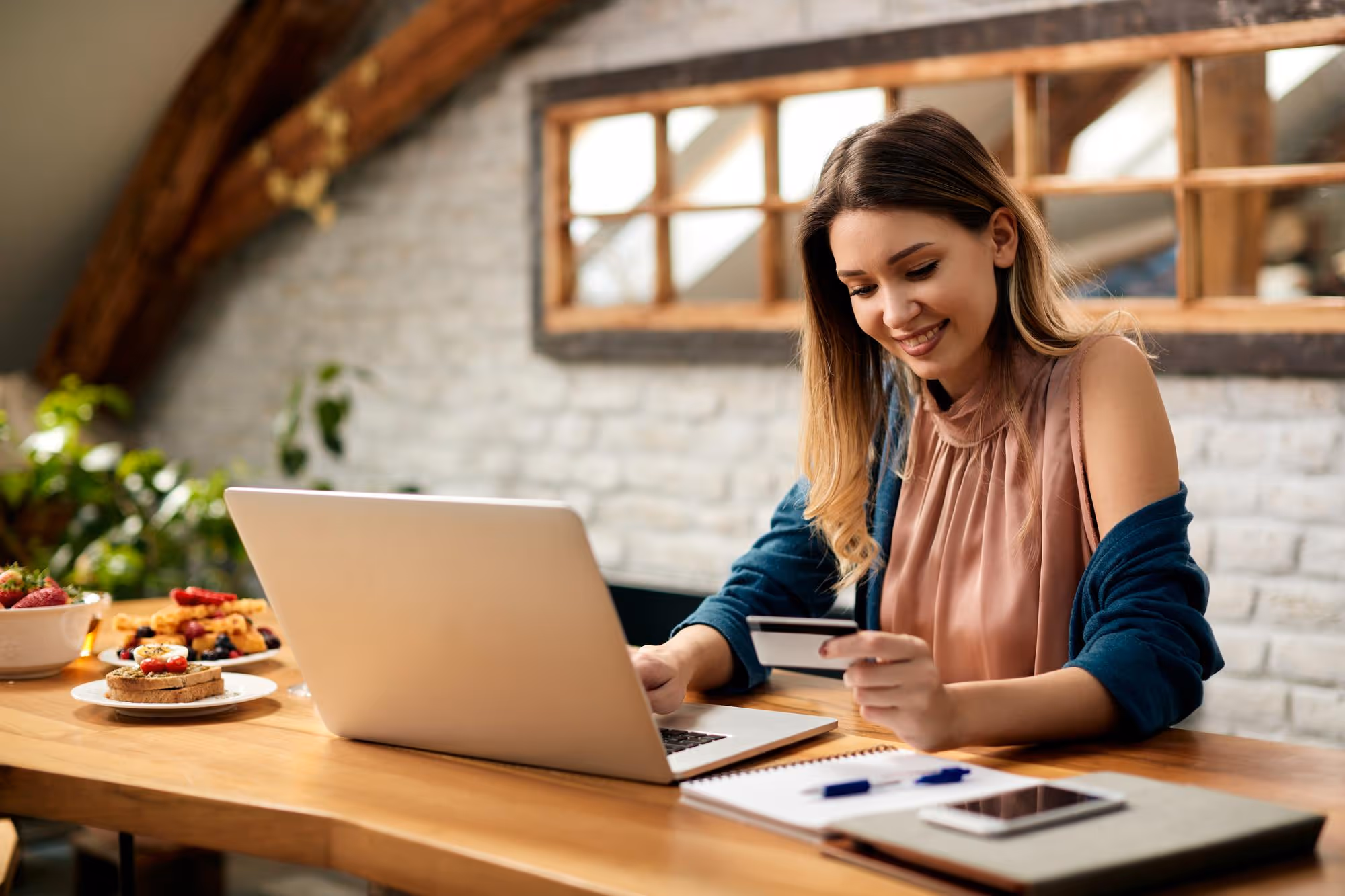 Woman holding a credit card and using a laptop, engaged in online home financing.