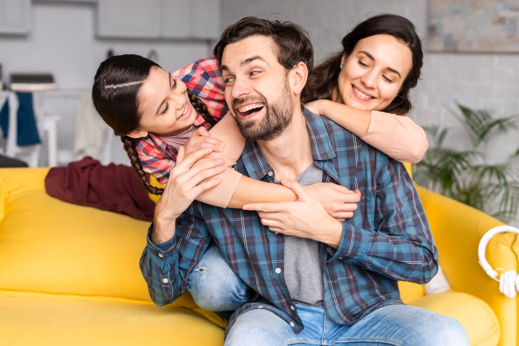 Happy family on yellow sofa inside their home.