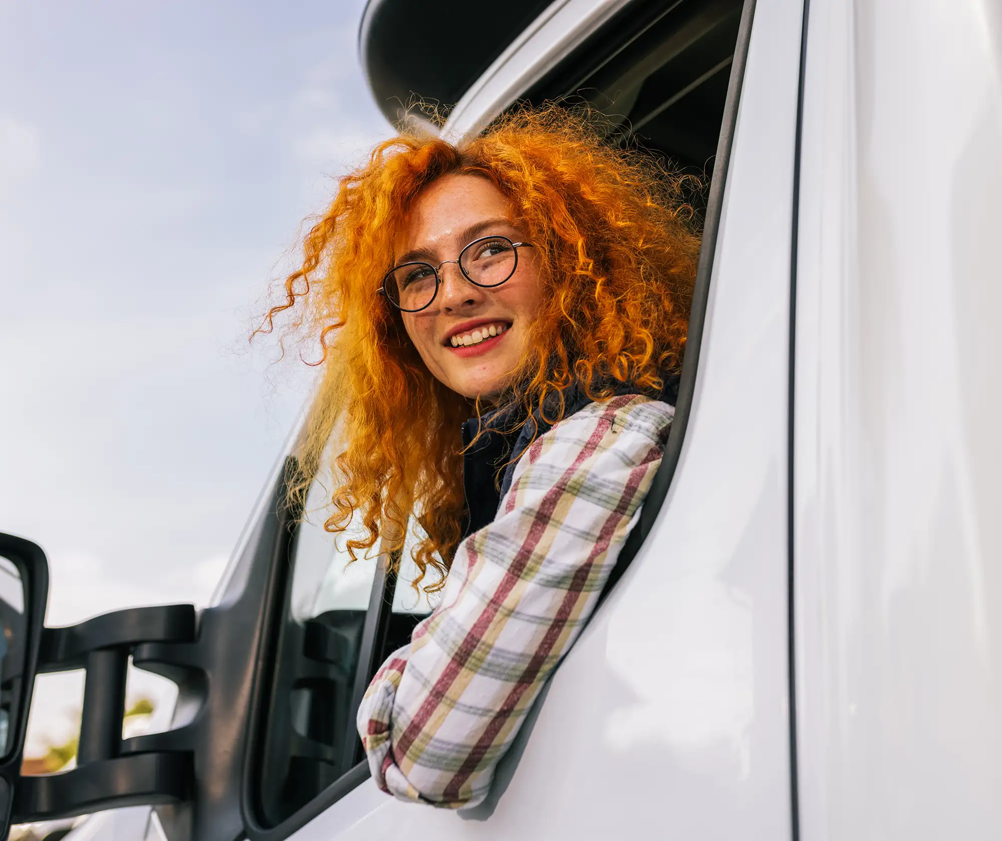 A woman with red hair driving a white truck