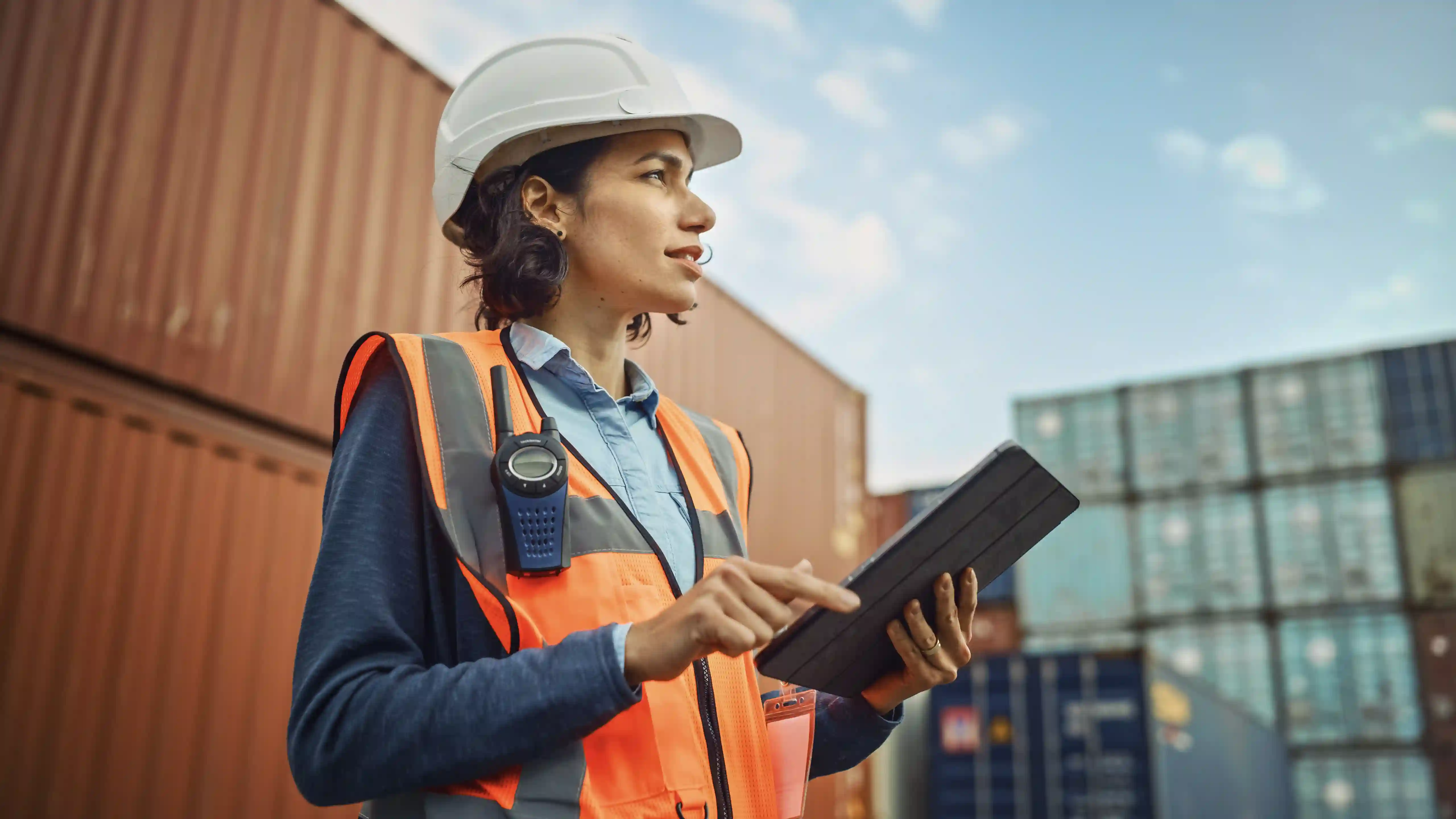 A woman worker in a blue jumpsuit looking far away and smiling
