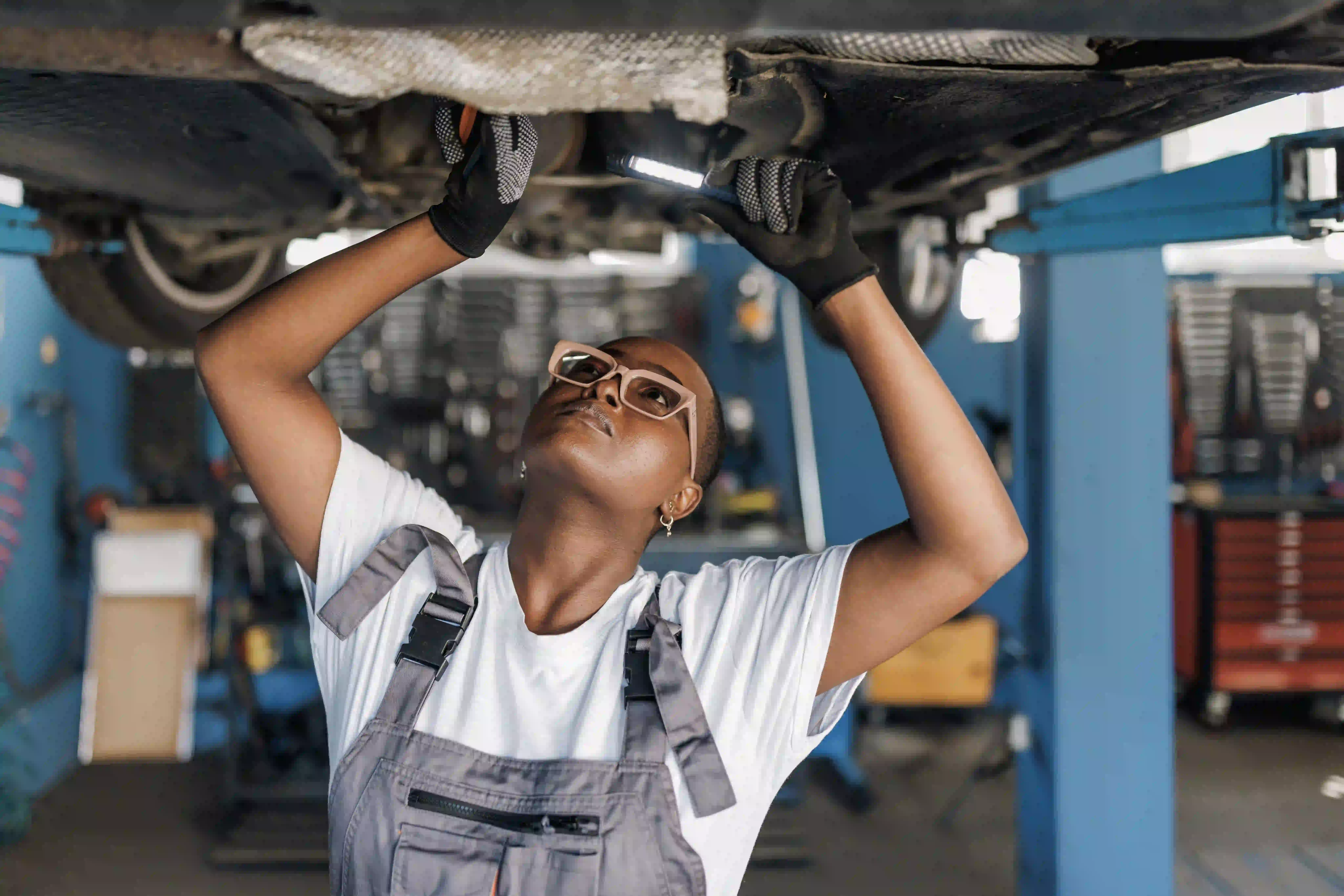 A woman worker in a blue jumpsuit looking far away and smiling