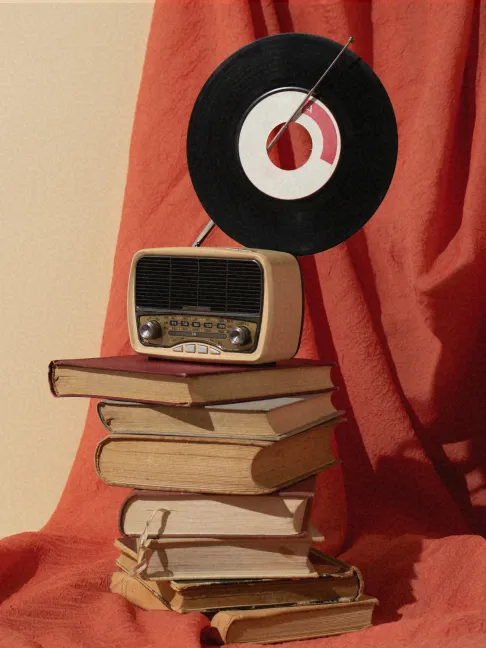 Stack of vintage books with red cloth draping and vinyl record on top