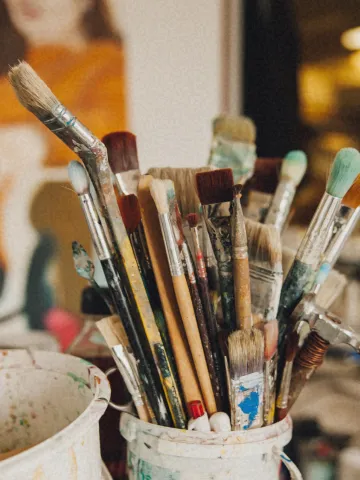 Collection of artist paintbrushes standing upright in container