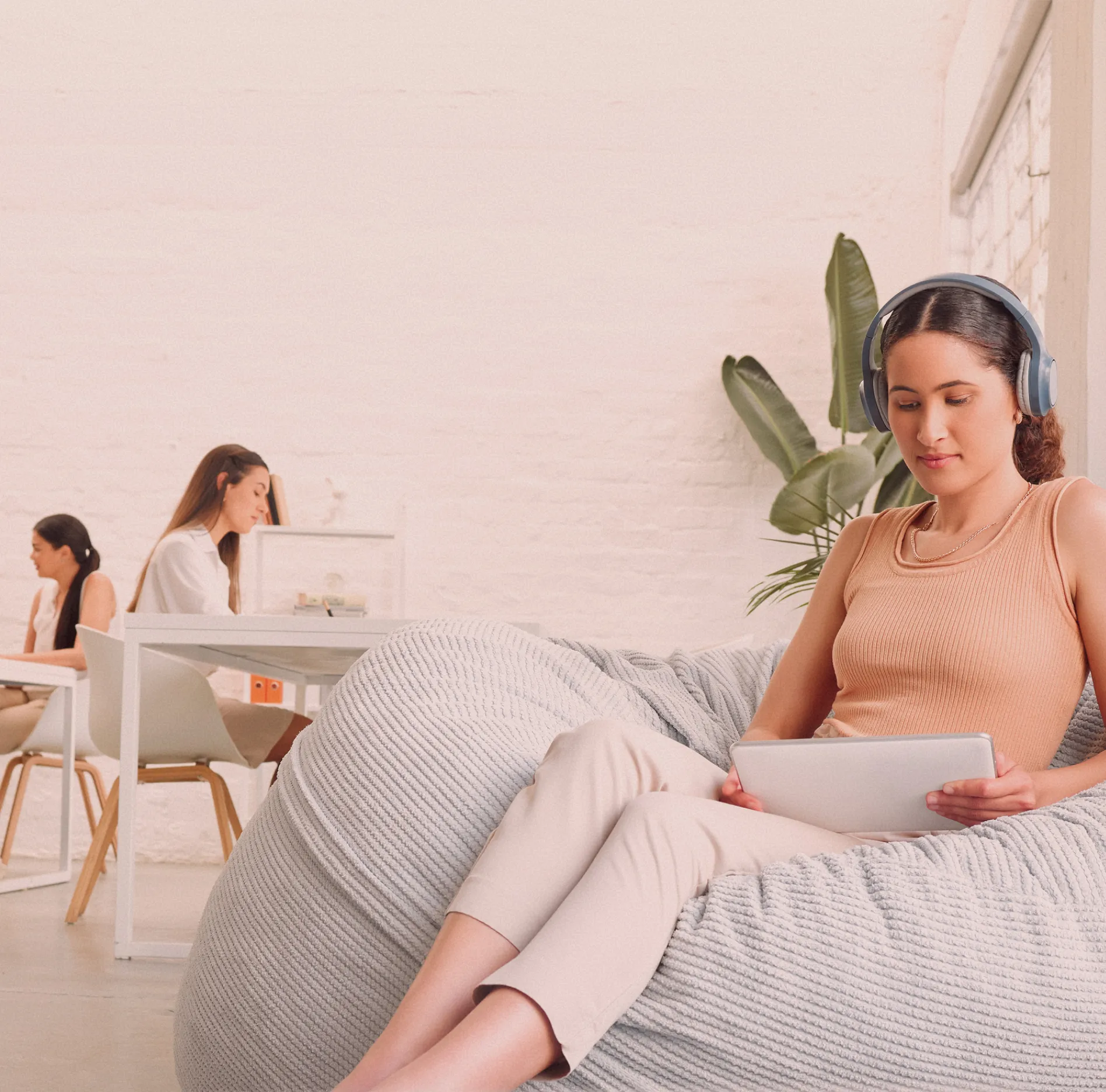 Woman lounging comfortably on a beige couch in a relaxed, modern interior space.
