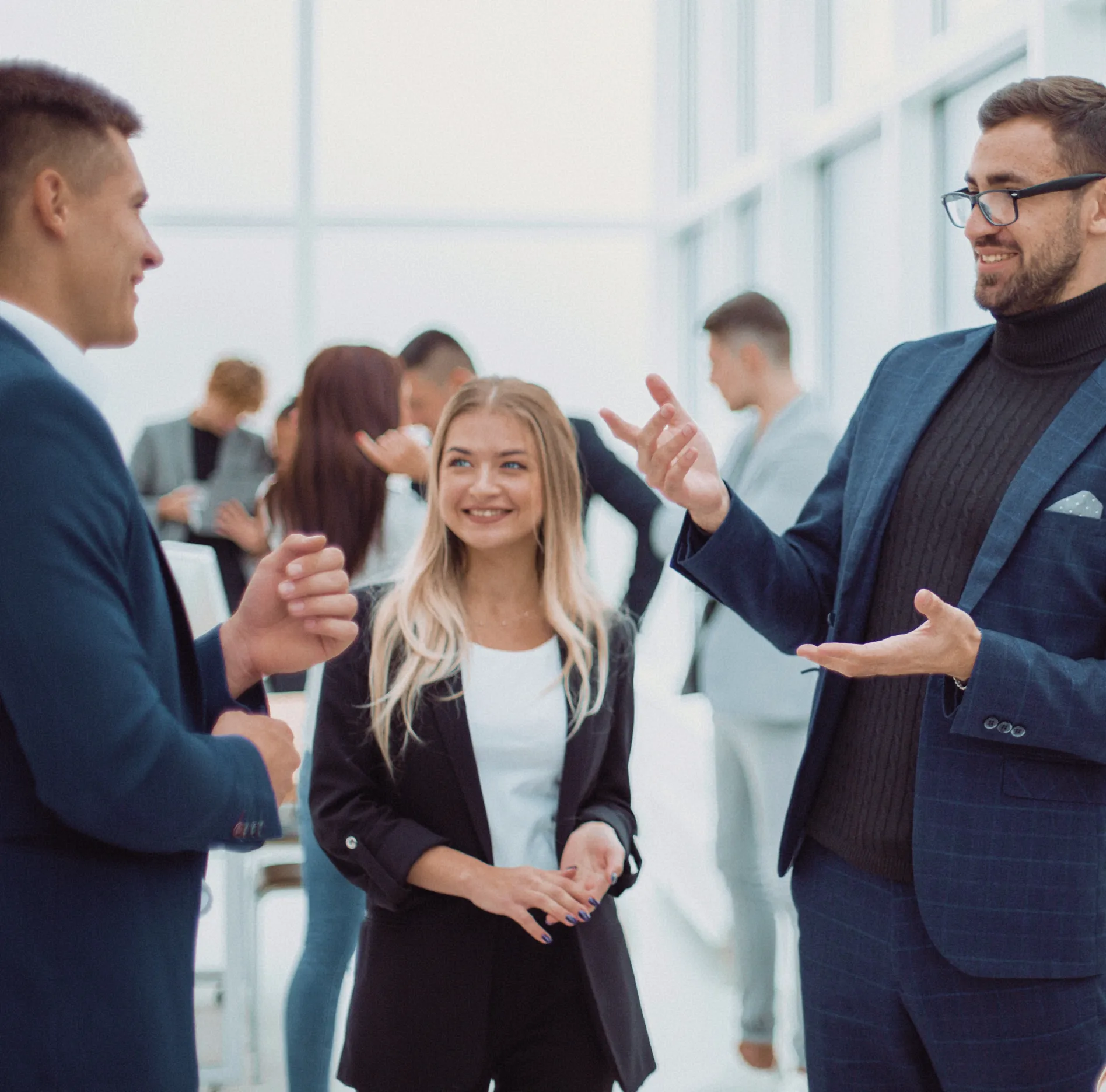 Business networking event with professionals in suits and formal attire engaging in conversation.