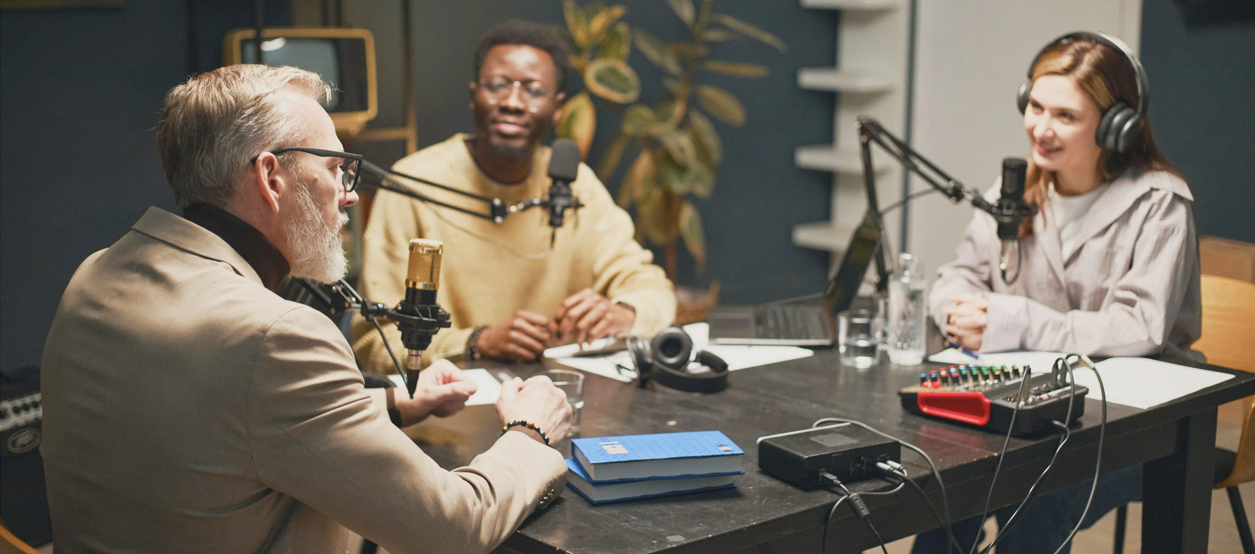 Panel of professionals recording a podcast or talk show with microphones and headphones in a cozy studio.