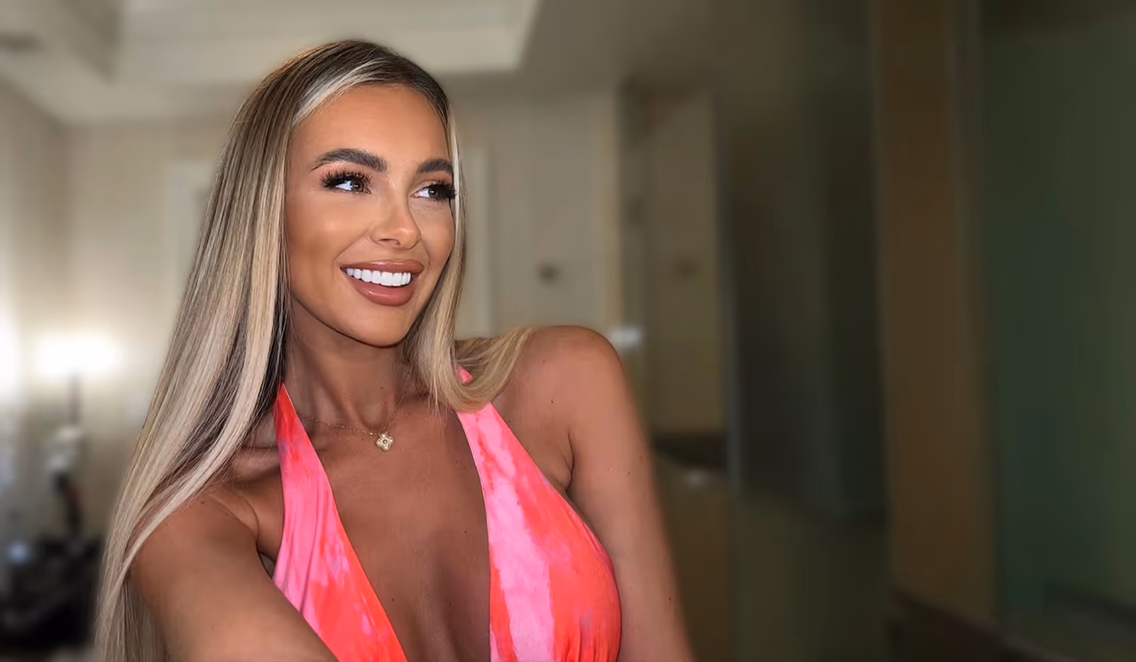 A woman in a pink dress posing for a picture.