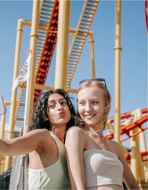 Two Girls posing in front of a Rollercoaster