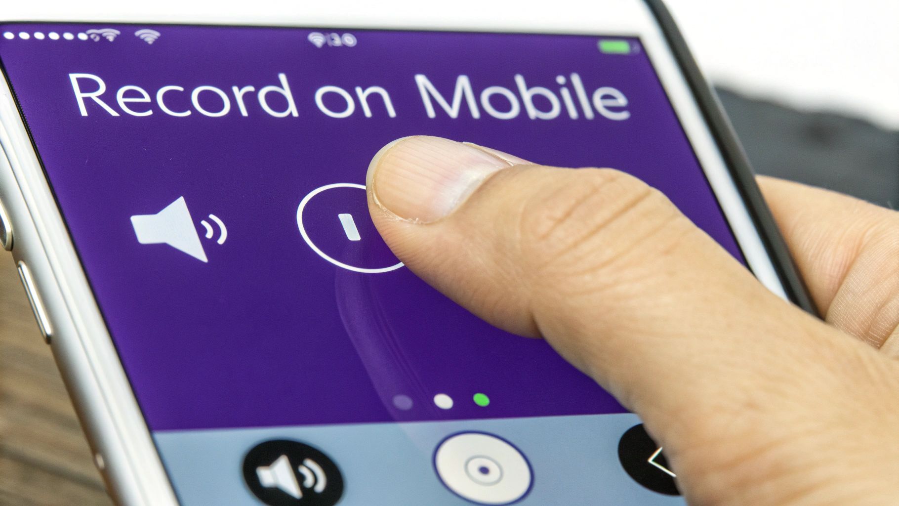 A smartphone in a user's hand, displaying a screen recording in progress with audio waves visible on the screen.