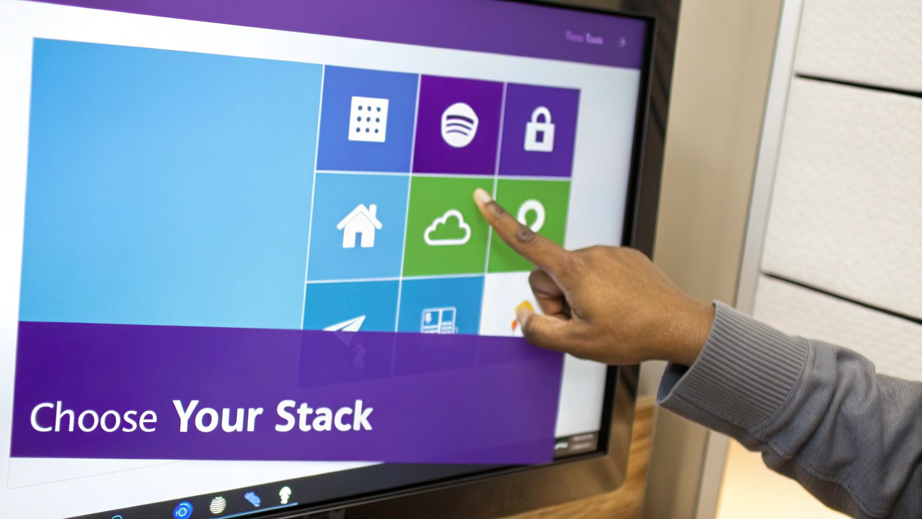 A person's hand interacting with a touchscreen display showing a grid of colorful icons and text.