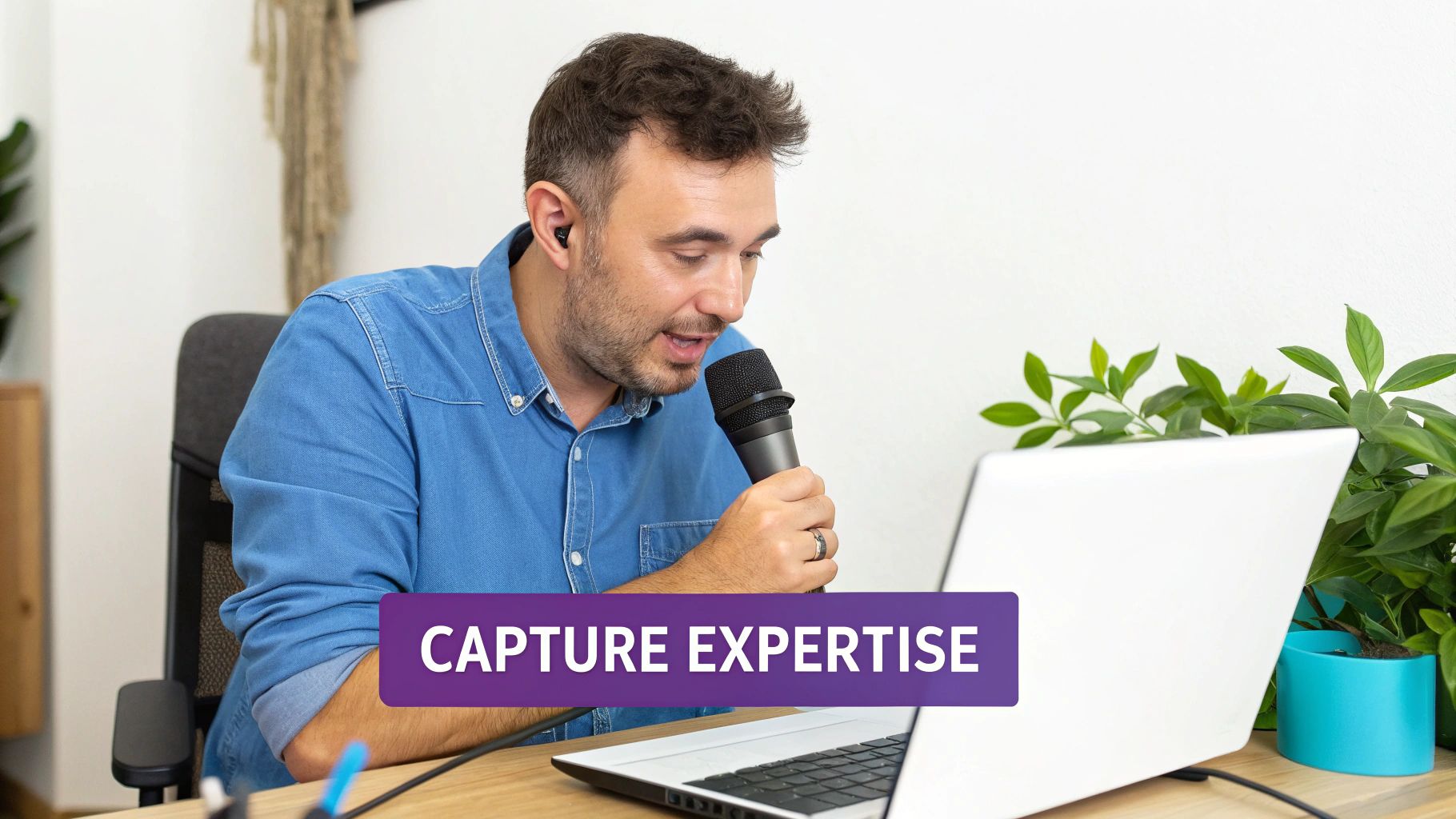 Man recording a podcast or online training, speaking into a microphone, looking at a laptop.