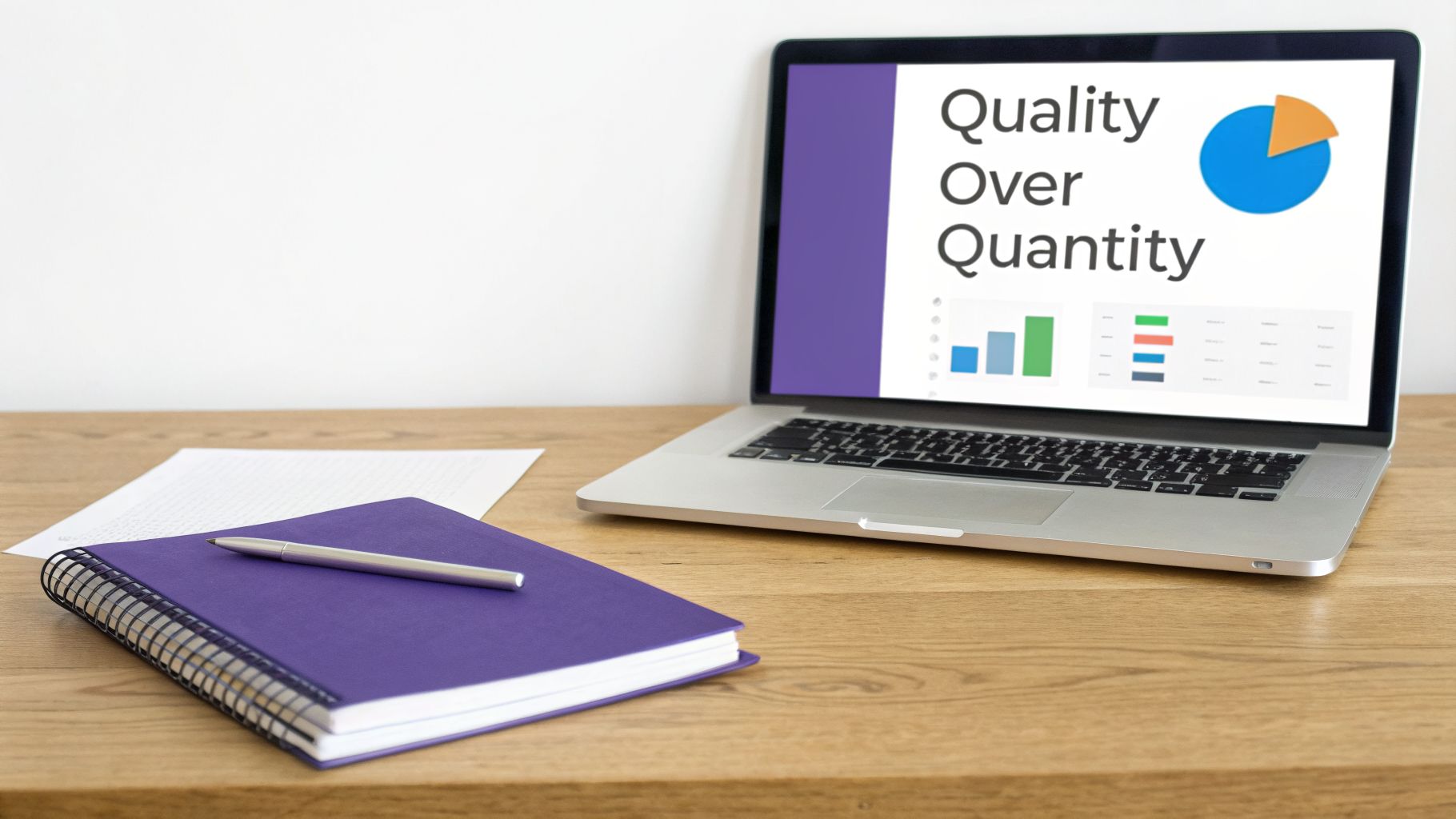 A laptop displaying a 'Quality Over Quantity' presentation on a wooden desk with a notebook and pen.