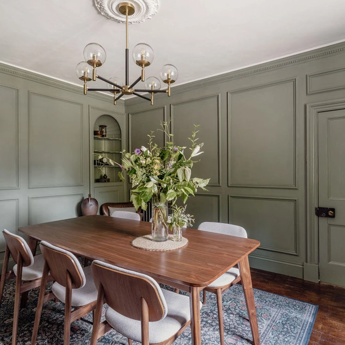 Elegant dining room interior design features wooden furniture and green paneled walls beautifully.